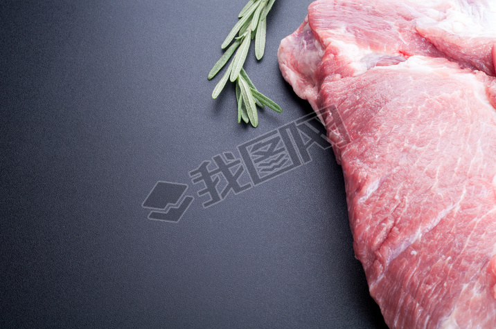 Raw meat and rosemary on dark background