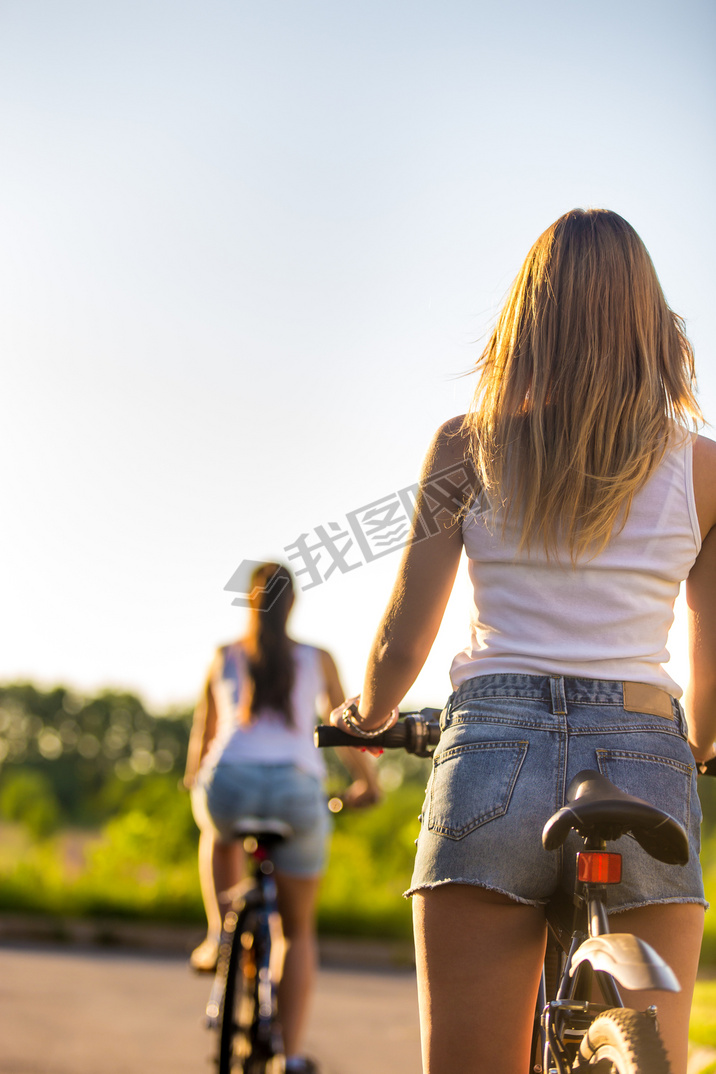 Young women on bikes, rear view