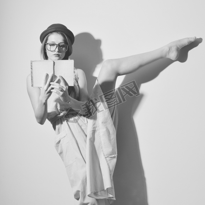 Portrait of elegant gymnast in a hat and glasses reading a book
