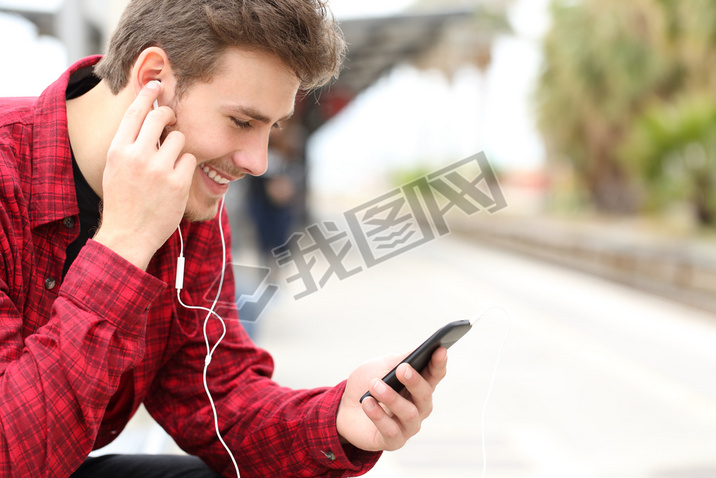 Man listening to the music waiting in a train station