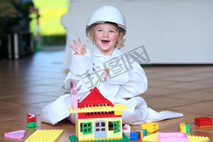 Toddler girl wearing safety helmet playing with building blocks