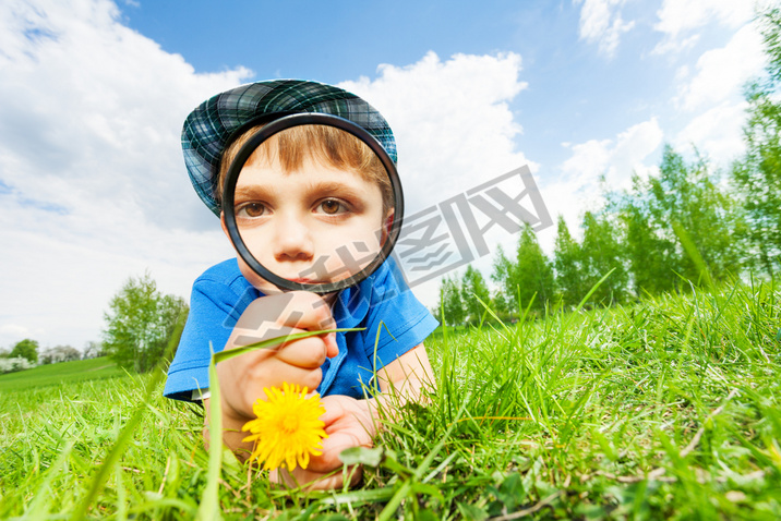Small boy with magnifier and yellow flower