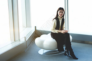 Young Japanese businesswoman with mobile phone in hands is waiting international partners in airport