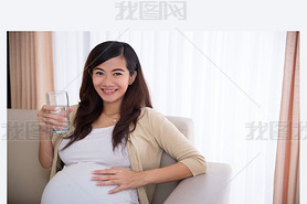 Pregnant asian woman drinking a glass of water