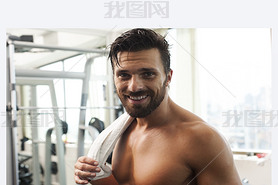 Young strong fit man iling, exercising in the gym