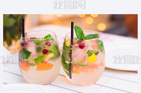 limonade with berries in glassware on wooden table on light blur