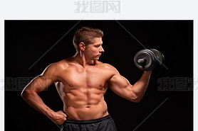 Shirtless y muscular sportan pumping up biceps with black dumbbell