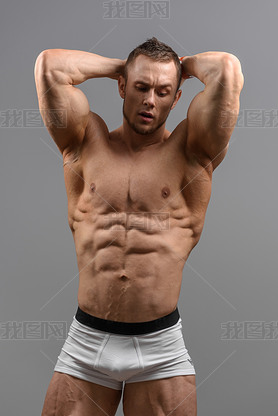 Shirtless athletic man posing over grey background in white underwear