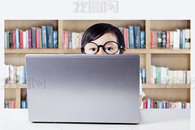 Child with laptop on desk peeping in library