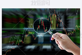 Hand holding magnifying glass with stock market graph background