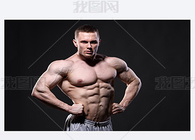 Strong muscular man posing in studio over dark background 