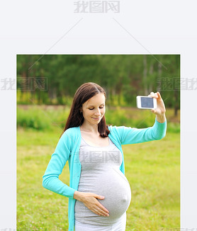 Happy young pregnant woman makes self-portrait on the artphone