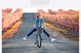 Pretty young woman with a vintage bike enjoying the time in cherry field in springtime.