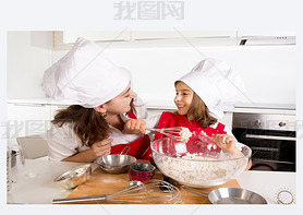 happy mother baking with little daughter in apron and cook hat with flour dough at kitchen