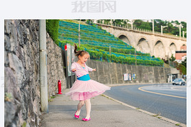 Outdoor portrait of a cute little girl of 7 years old, walking to dance school and dancing in the st