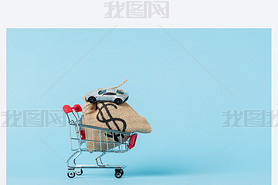 little shopping trolley with dollar bag and toy car on blue, leasing concept