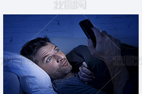 man in bed couch at home late at night using mobile phone in low