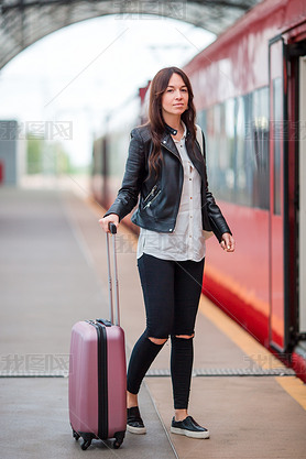 Young woman with luggage talking at train station. Caucasiam tourist waiting her express train while