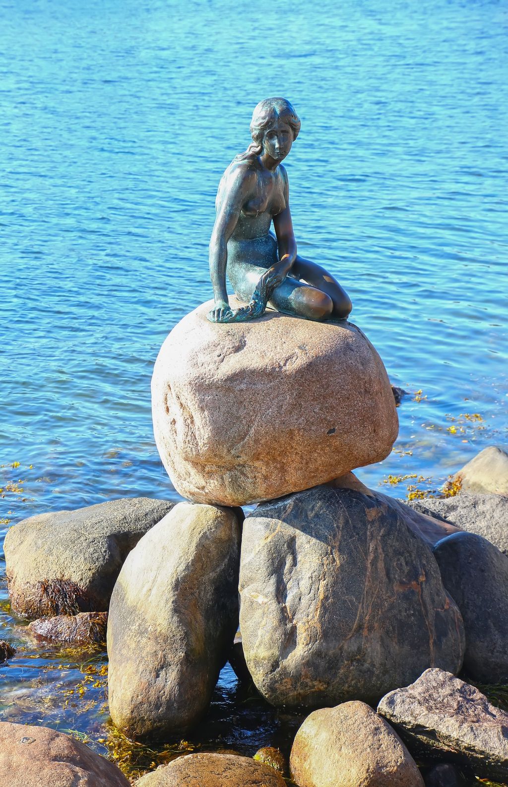 小美人鱼雕像和地标这是一个青铜做的女孩坐在一块大石头上该雕塑陈列