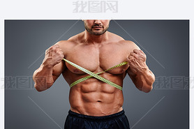 Bodybuilder measuring waist with tape measure