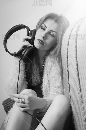 Picture of sexy pretty young lady hing fun enjoying music from headphones. Black and white photogr