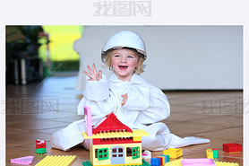 Toddler girl wearing safety helmet playing with building blocks