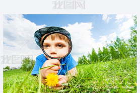 Small boy with magnifier and yellow flower