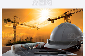 Safety helmet and architect pland on wood table with sunset scen