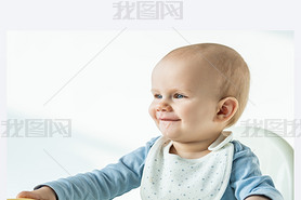 Smiling baby boy with soiled mouth sitting on feeding chair on white background