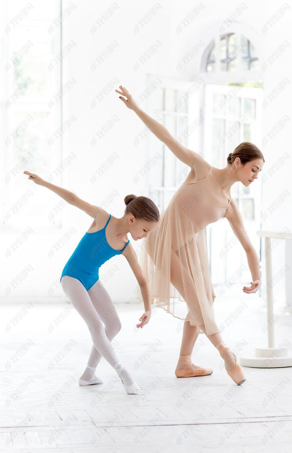 The little ballerina posing at ballet barre with personal teacher in dance studio