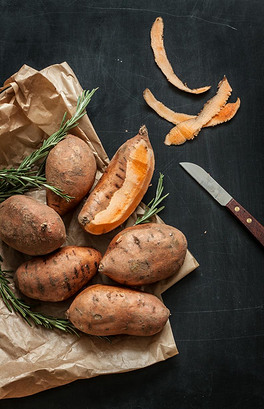 Peeling sweet potatoes with knife on black chalkboard