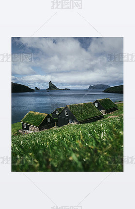 Black wooden houses with a green grass roof. Houses by the ocean overlooking the cliffs of the Faroe