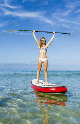 Woman with arms up and learning paddle-surf