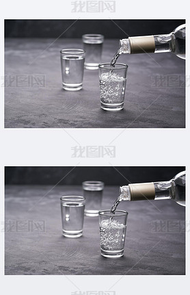 Pouring vodka into the glass on a black background, selective focus