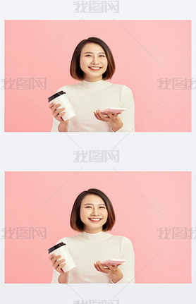 Close up portrait of young Asian woman holding coffee cup and artphone over pink background.