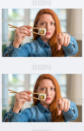 Redhead woman eating sushi using chopsticks pointing with finger to the camera and to you, hand sign