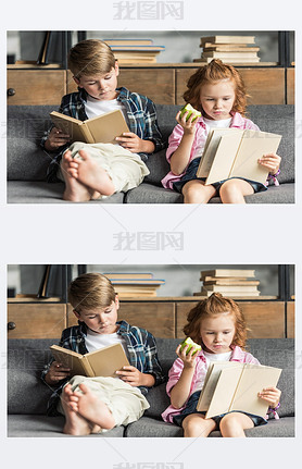 concentrated little brother and sister reading books on couch at home