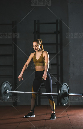 Young caucasian sportswoman letting go barbell  in sports hall