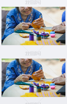 Elderly woman with caregiver in the needle crafts occupational therapy for Alzheimers or dementia