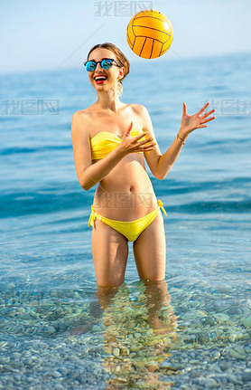 Woman with yellow ball in the sea