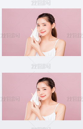 Young attractive Asian woman using hygiene wiper sheet to clean her face skin isolated on pink backg