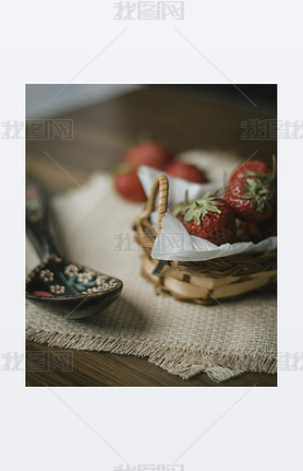 Close-up view of strawberries in wicker bowl on table. Mellow strawberries in basket on tablecloth w