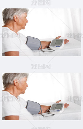 Elder woman measuring blood pressure with automatic manometer at