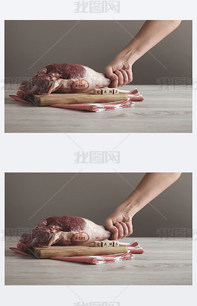 Hand holds raw lamb leg meat on table