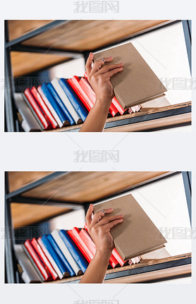 Cropped shot of student holding book at bookshelf in library 