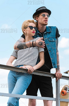 原创男友纹身拥抱时尚的女朋友他们靠在栏杆上版权可商用
