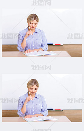 Teacher at the desk checking her register.