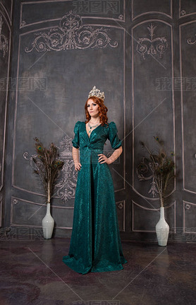 Gorgeous young woman in luxury dress and diamond crown posing in vintage room