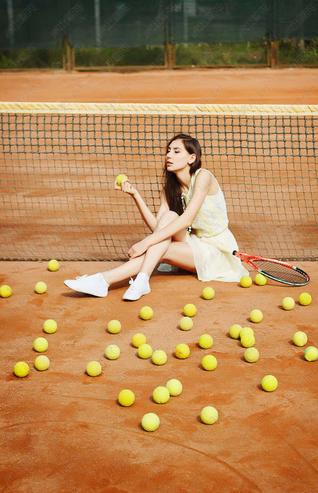 年轻漂亮的黑发女子在球场上打网球的照片