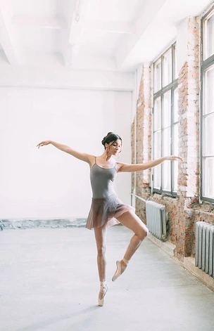 一个年轻的芭蕾舞演员正在准备, 伸展和跳舞。在芭蕾中摆姿势。在阁楼工作室拍照片。在板凳上的俄罗斯芭蕾舞演员。芭蕾公寓和舞蹈礼服